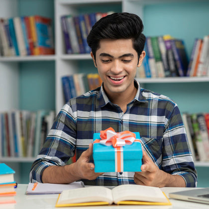 College student in his dorm at his desk holding a gift of Sconza Chocolate