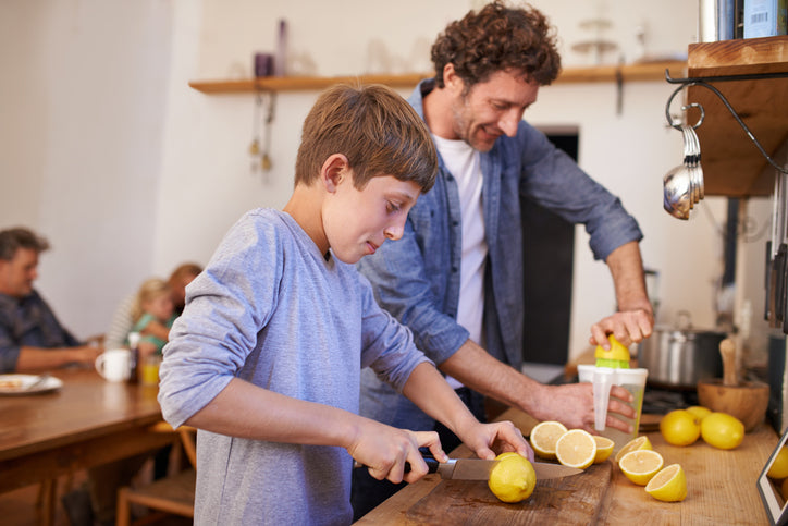 A cropped portrait of a happy father and son making lemonade in their kitchen at home